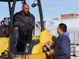 One Worker on a CAT Forklift Discussing with Another Worker