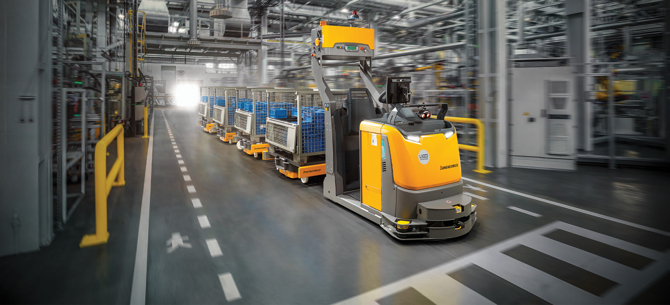 Jungheinrich automated tow tractor in warehouse pulling carts