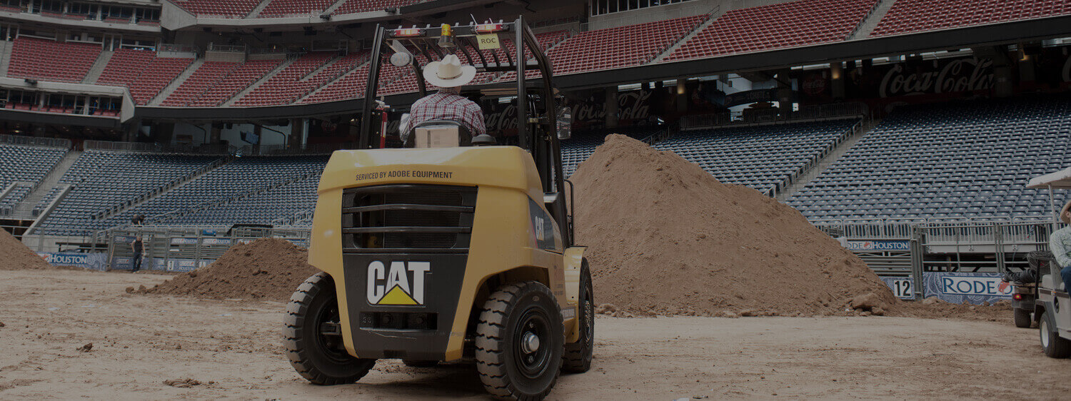 Man Wearing a Cowboy Hat Driving a CAT Forklift in the Rodeo Stadium
