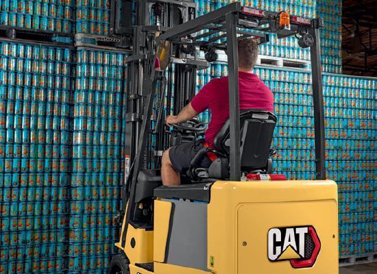 Rear view of worker picking up pallet with Cat small electric cushion forklift